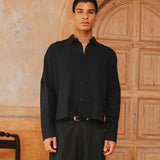 Man wearing a black shirt and pants standing in front of a wooden door.